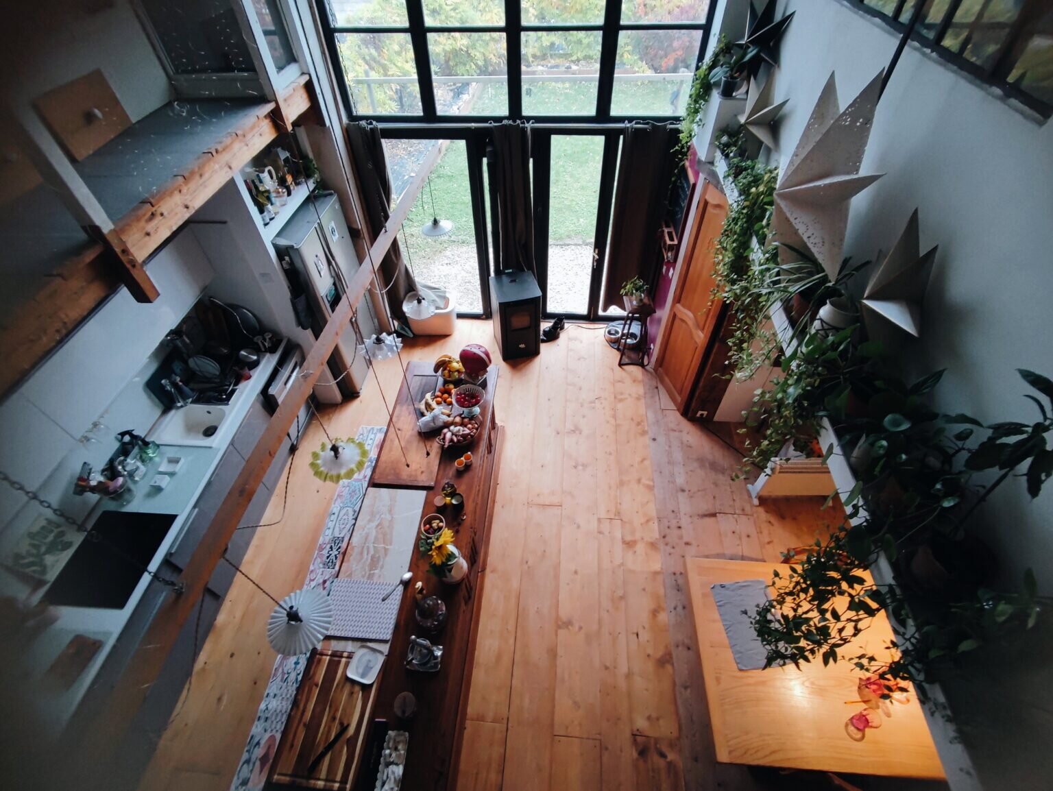 La grande salle du gîte vue d'en haut, avec la longue table et les plantes